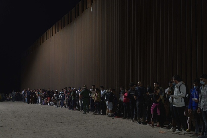 Migrants wait to be processed by US Border Patrol after illegally crossing the US-Mexico border in Yuma, Arizona in the early morning of July 11, 2022. (Photo by ALLISON DINNER/AFP via Getty Images)