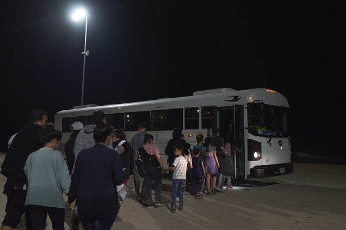 US Border Patrol agents direct migrants to a bus for processing after they illegally crossed the US-Mexico border in Yuma, Arizona, early in the morning of July 11, 2022. (Photo by ALLISON DINNER/AFP via Getty Images)