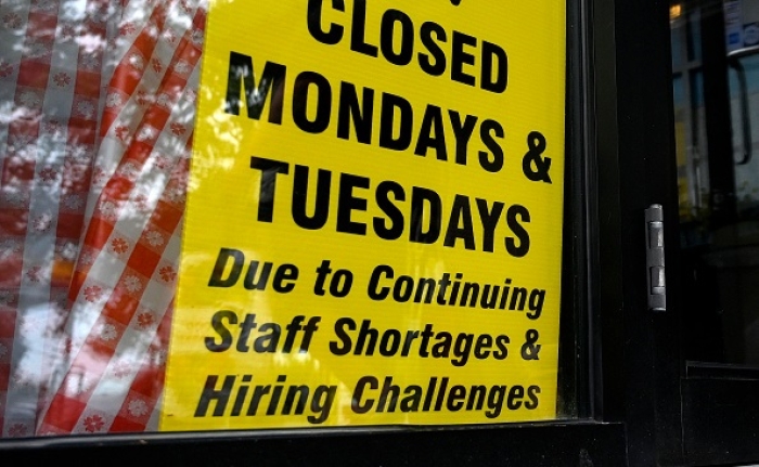 A shop displays a sign announcing reduced store hours due to a labor shortage, on July 29, 2022 in Arlington, Virginia. (Photo by OLIVIER DOULIERY/AFP via Getty Images)