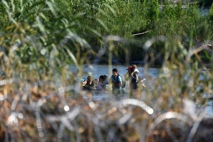 A migrant family from Venezuela illegally cross the Rio Grande River in Eagle Pass, Texas, at the border with Mexico on June 30, 2022. (Photo by CHANDAN KHANNA/AFP via Getty Images)