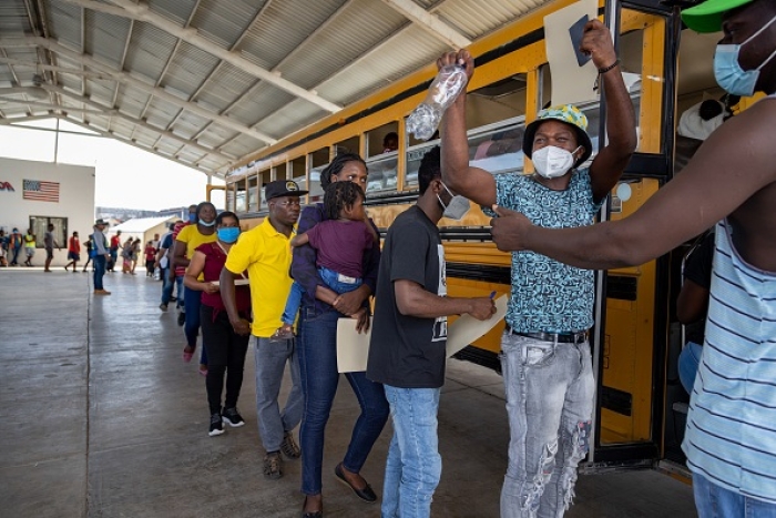 A Haitian migrant approved for humanitarian parole cheers as he boards a bus taking migrants into the U.S. on August 30, 2022 in Reynosa, Mexico. An estimated 6000 migrants, with a Haitian majority, continue to overwhelm the northern Mexican city of Reynosa, a town bordering McAllen, Texas, while waiting for an opportunity to cross into the United States. (Photo by Michael Nigro/Getty Images)