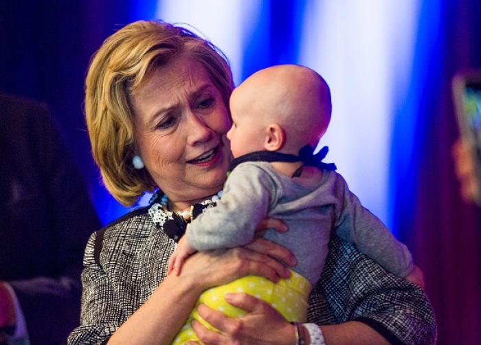 Former Secretary of State Hillary Clinton greets a baby in the crowd at a book signing. (File Photo by Brooks Kraft LLC/Corbis via Getty Images)