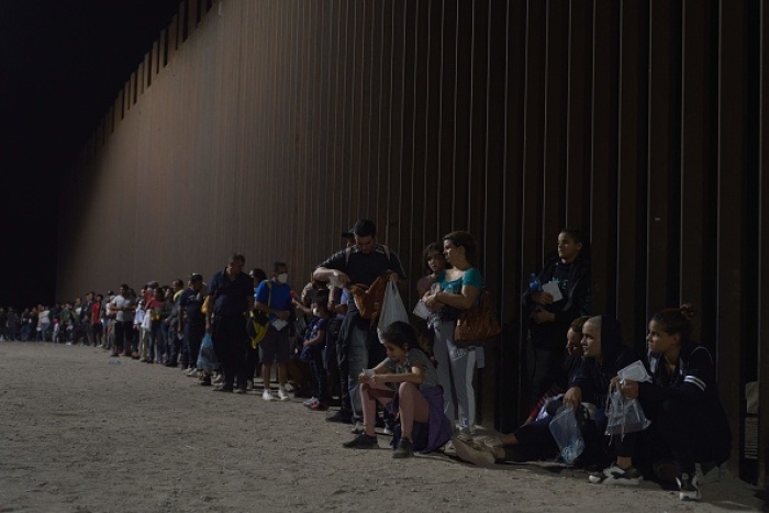 Migrants wait to be processed by US Border Patrol after illegally crossing the US-Mexico border in Yuma, Arizona. (Photo by ALLISON DINNER/AFP via Getty Images)