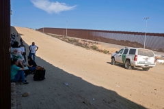 A Border Patrol passes by a group of more than 50 asylum seekers, mainly from South America, wait for US authorities to process them after crossing the US-Mexico border fence, as seen from Tijuana, Baja California State, Mexico, on September 5, 2022. (Photo by GUILLERMO ARIAS/AFP via Getty Images)