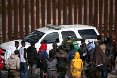 A border patrol agent talks to a group of migrants, mostly from African countries, before processing them after they crossed the US-Mexico border, taken from Tijuana, Baja California state, Mexico, on November 11, 2022. (Photo by GUILLERMO ARIAS/AFP via Getty Images)